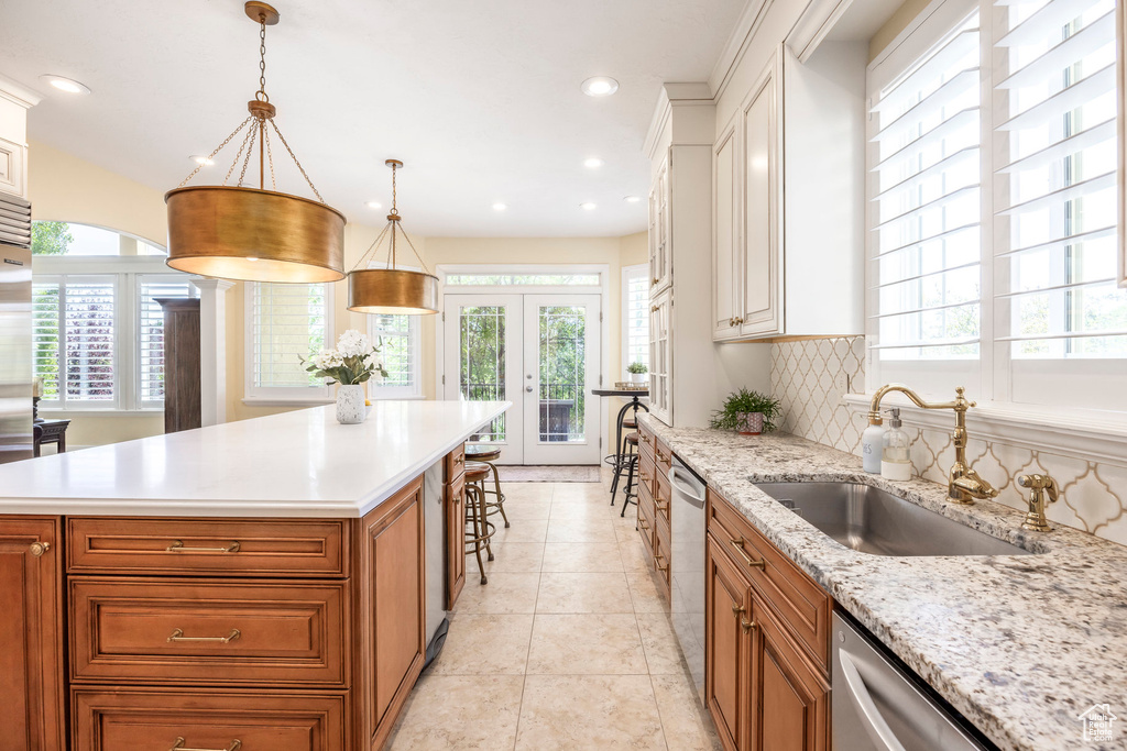 Kitchen featuring french doors, brown cabinetry, stainless steel dishwasher, tasteful backsplash, and recessed lighting