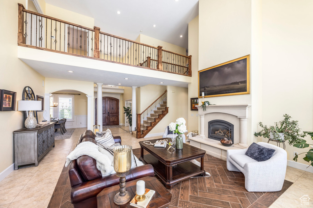 Living area with ornate columns, arched walkways, a towering ceiling, a glass covered fireplace, and recessed lighting