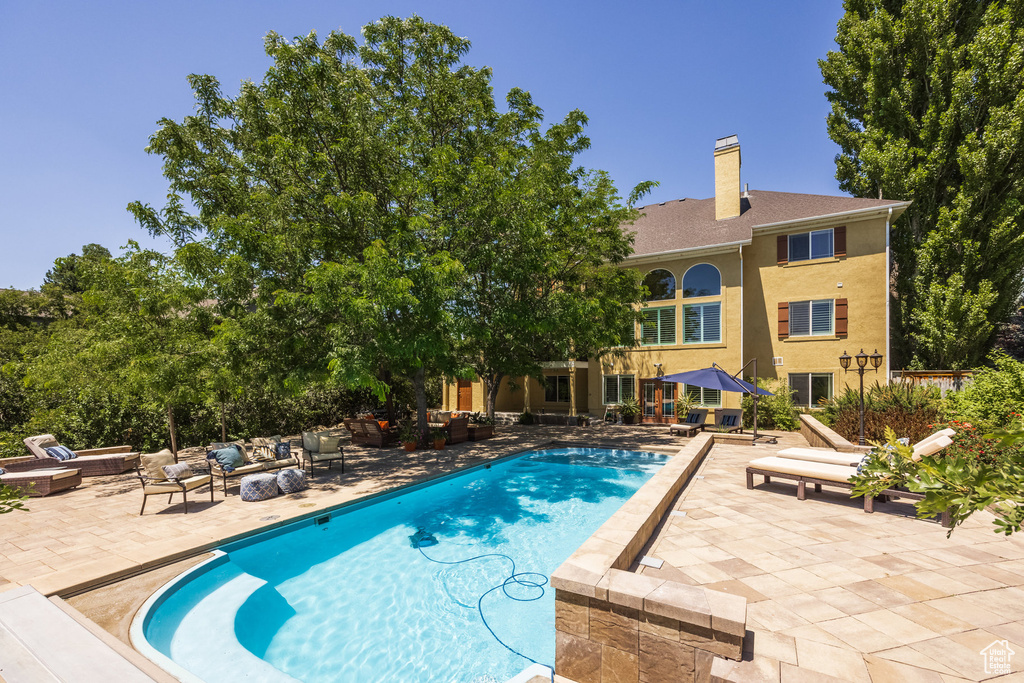 Outdoor pool with an outdoor living space with a fire pit and a patio