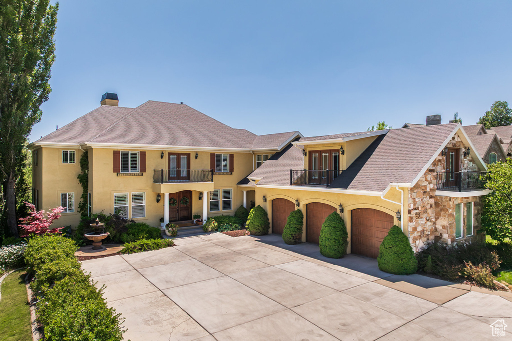 View of front of property with a balcony, french doors, a chimney, and stucco siding