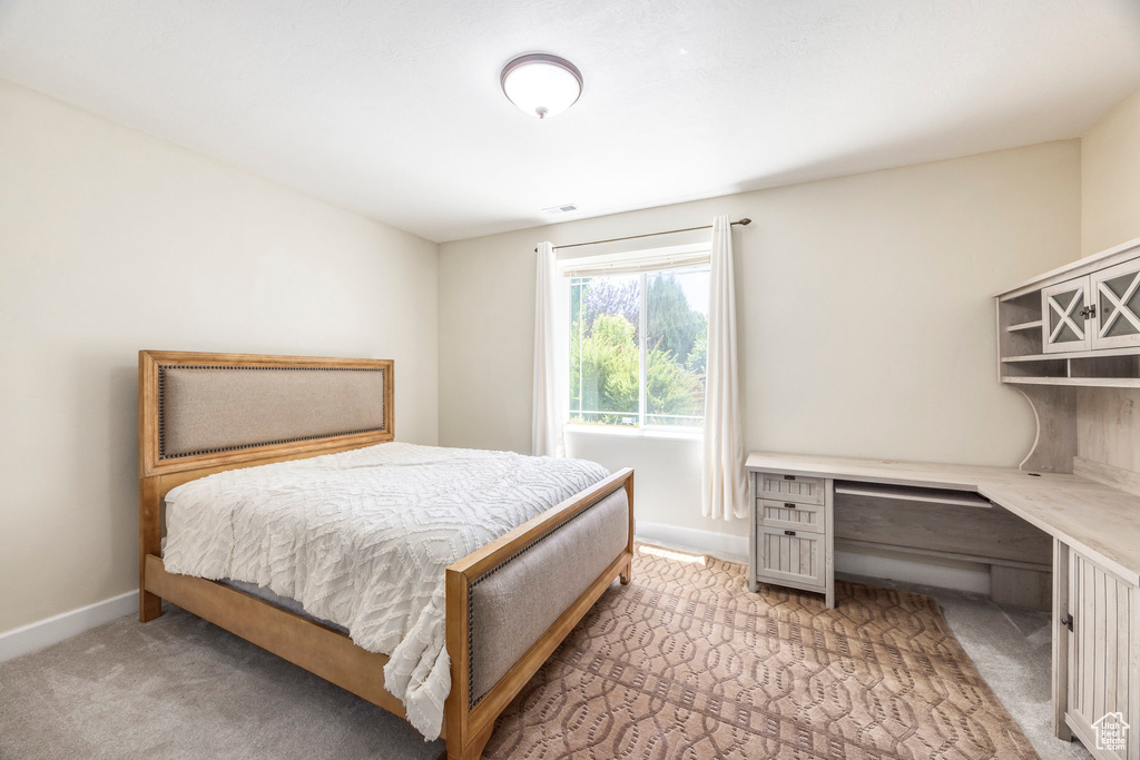 Bedroom featuring light carpet and an office area