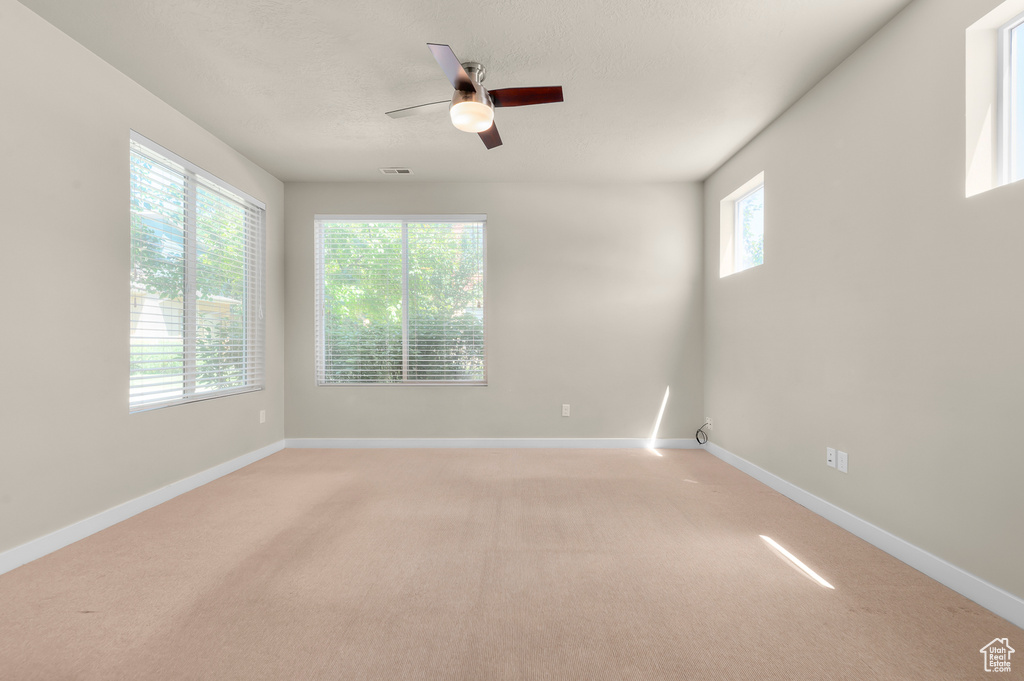 Spare room featuring light colored carpet and a ceiling fan