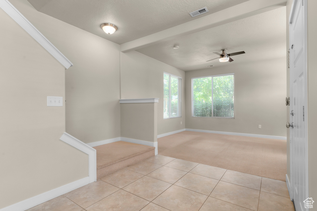 Unfurnished room with light colored carpet, light tile patterned flooring, and ceiling fan