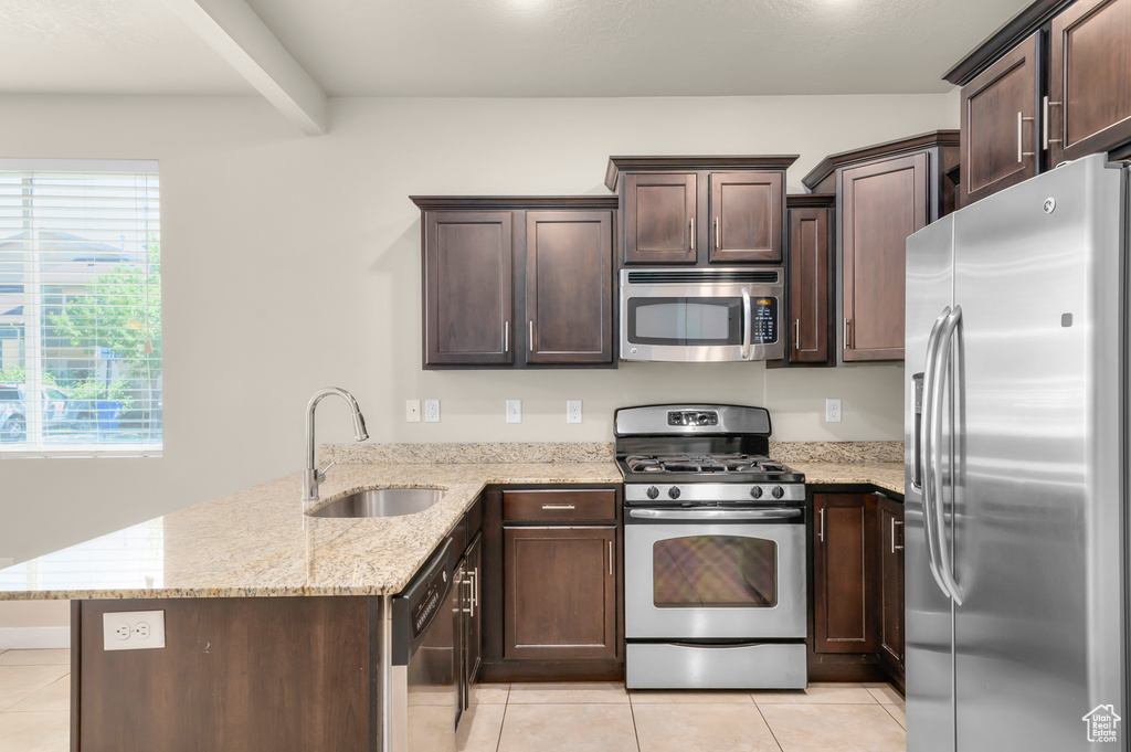 Kitchen with stainless steel appliances, a peninsula, light tile patterned floors, dark brown cabinets, and beam ceiling