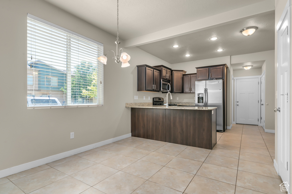 Kitchen with stainless steel appliances, dark brown cabinets, a peninsula, light tile patterned floors, and recessed lighting