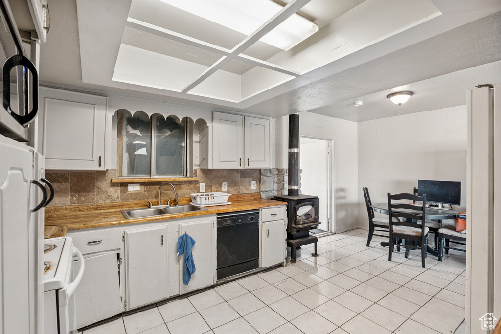 Kitchen with black dishwasher, white range oven, light countertops, decorative backsplash, and light tile patterned floors