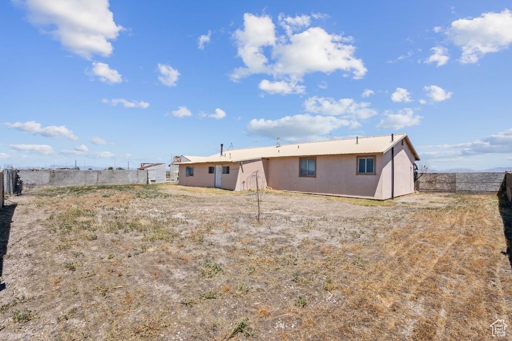 Back of property featuring a metal roof and stucco siding