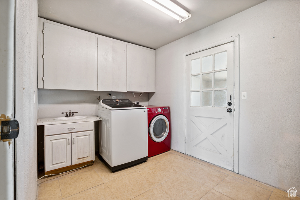 Laundry area with cabinet space, washer and dryer, and light tile patterned flooring