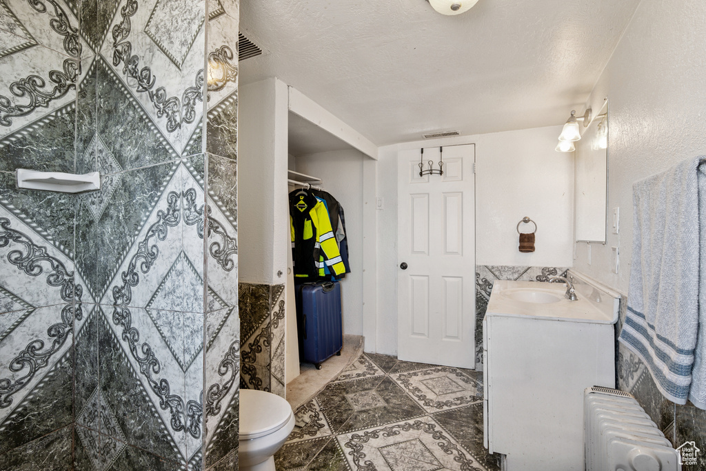 Full bath featuring radiator, vanity, and tile patterned floors