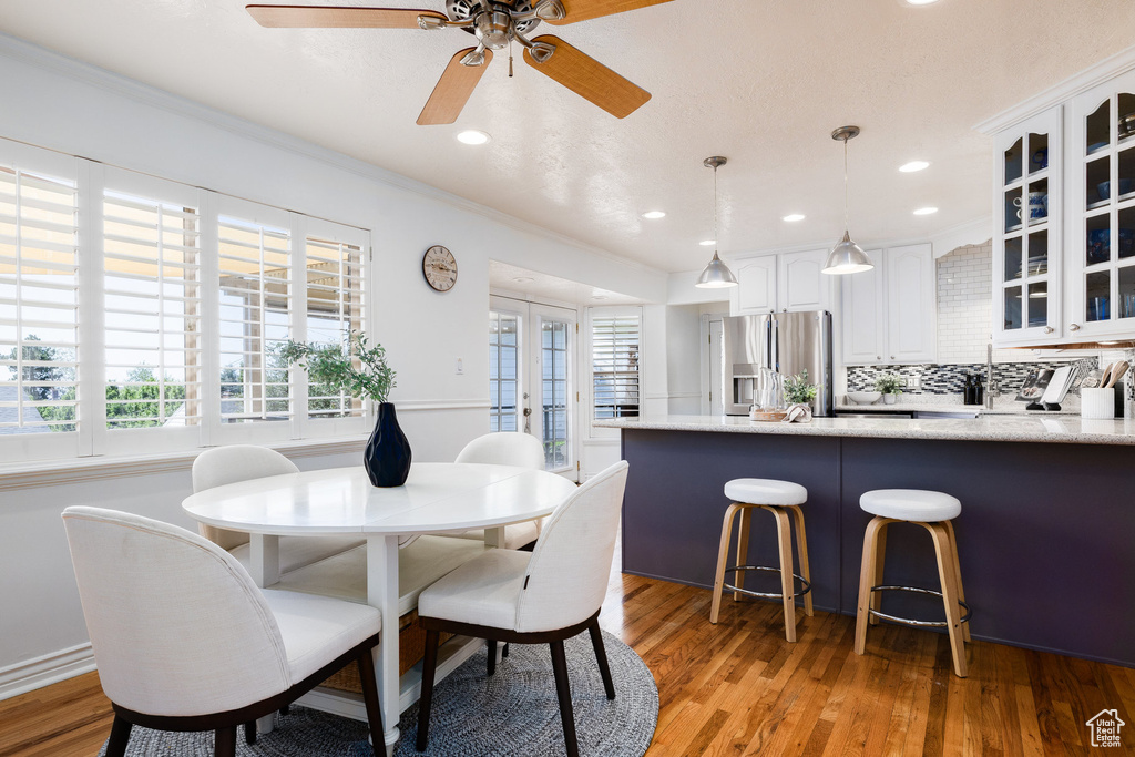 Dining space with light wood finished floors, a ceiling fan, ornamental molding, and recessed lighting