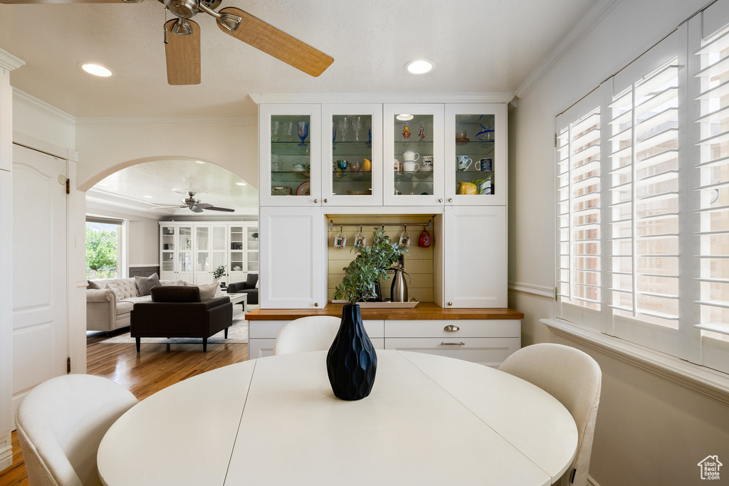 Dining area with a ceiling fan, crown molding, wood finished floors, arched walkways, and recessed lighting