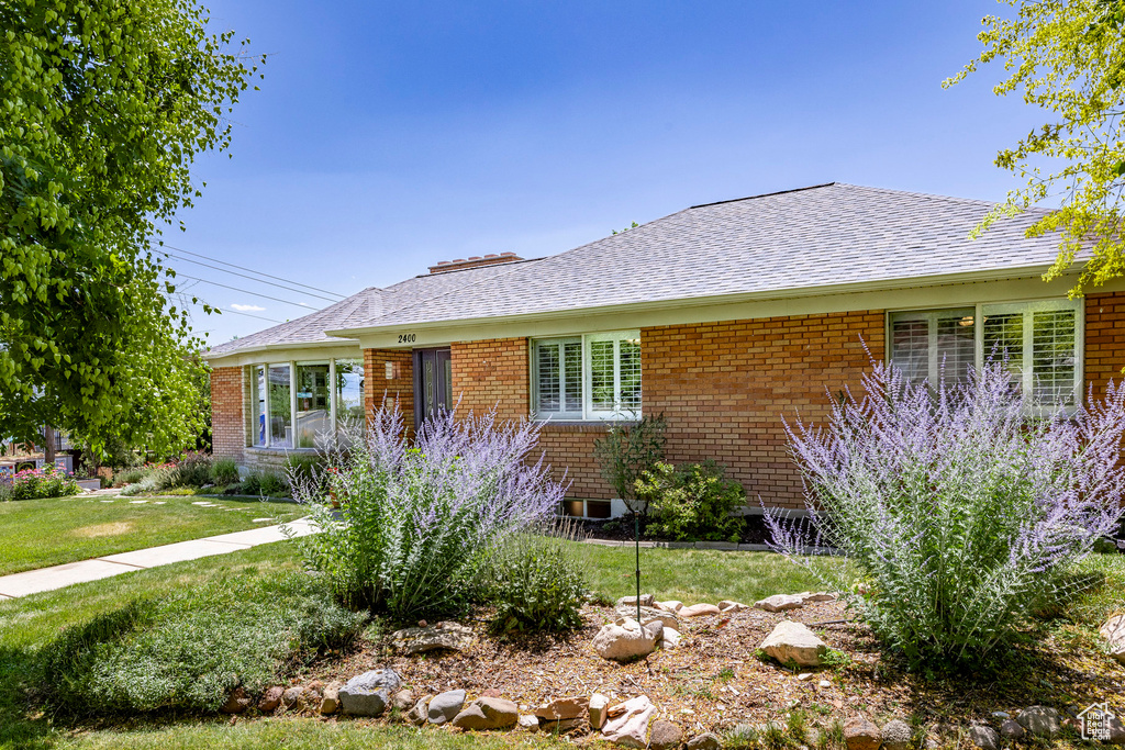 View of front of house with brick siding, a front lawn, and a shingled roof