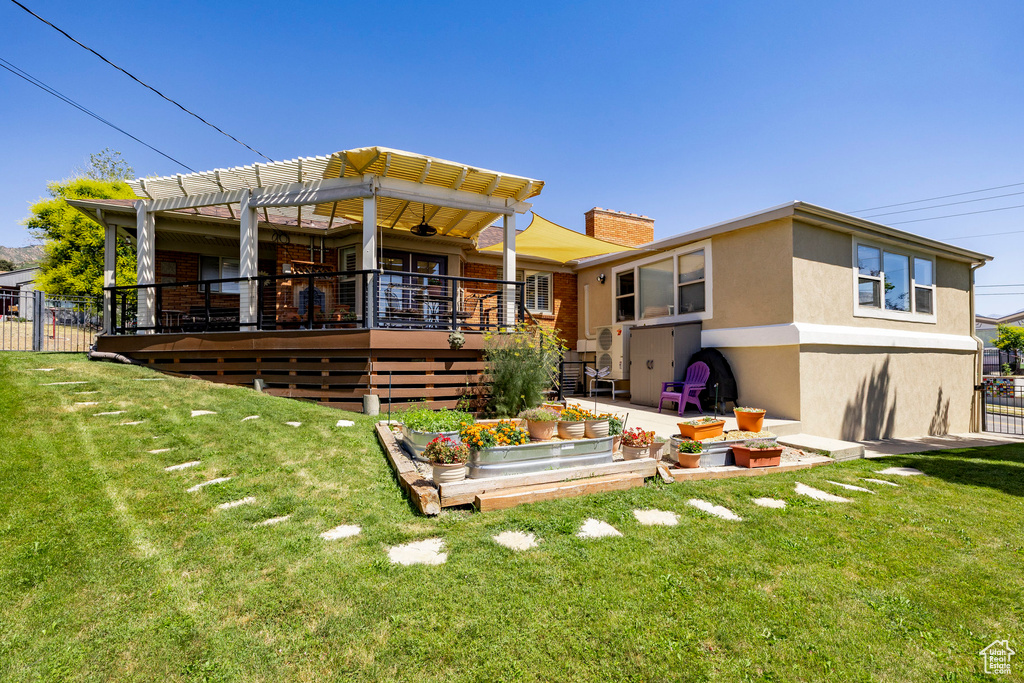 Rear view of house with a chimney, stucco siding, a pergola, a wooden deck, and a garden