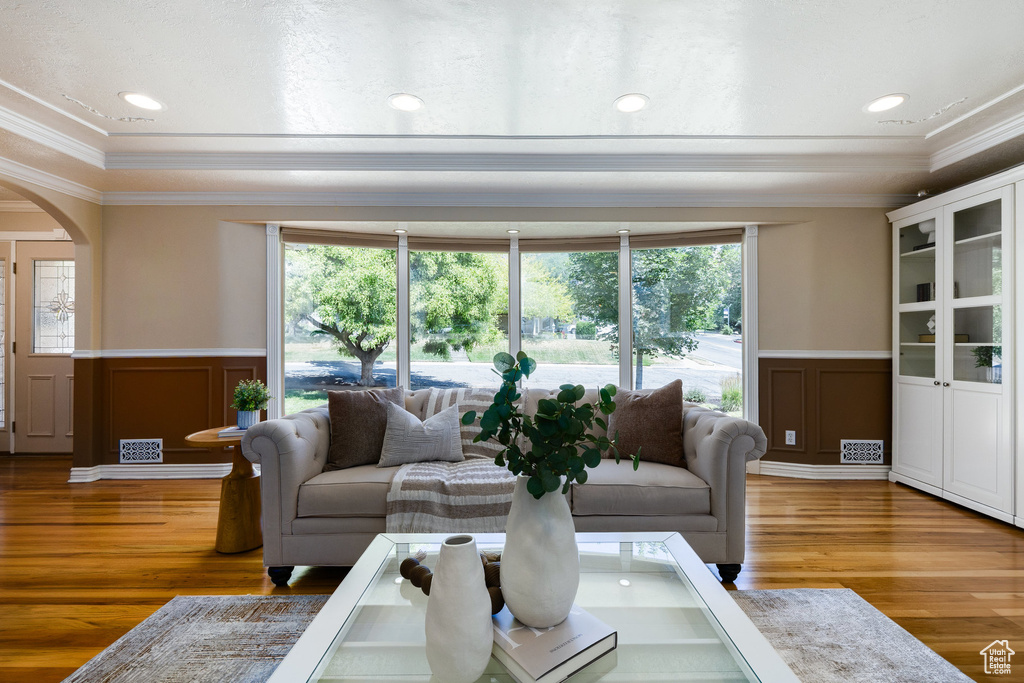 Living area featuring a decorative wall, crown molding, wainscoting, arched walkways, and healthy amount of natural light