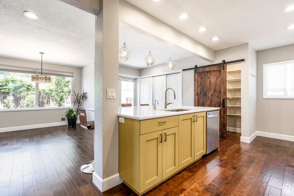 Kitchen with dishwasher, a barn door, light countertops, dark wood-style flooring, and recessed lighting