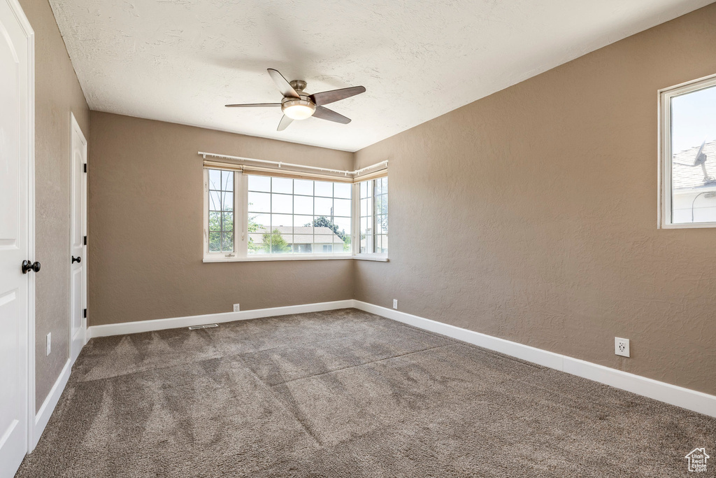 Carpeted spare room featuring ceiling fan and baseboards