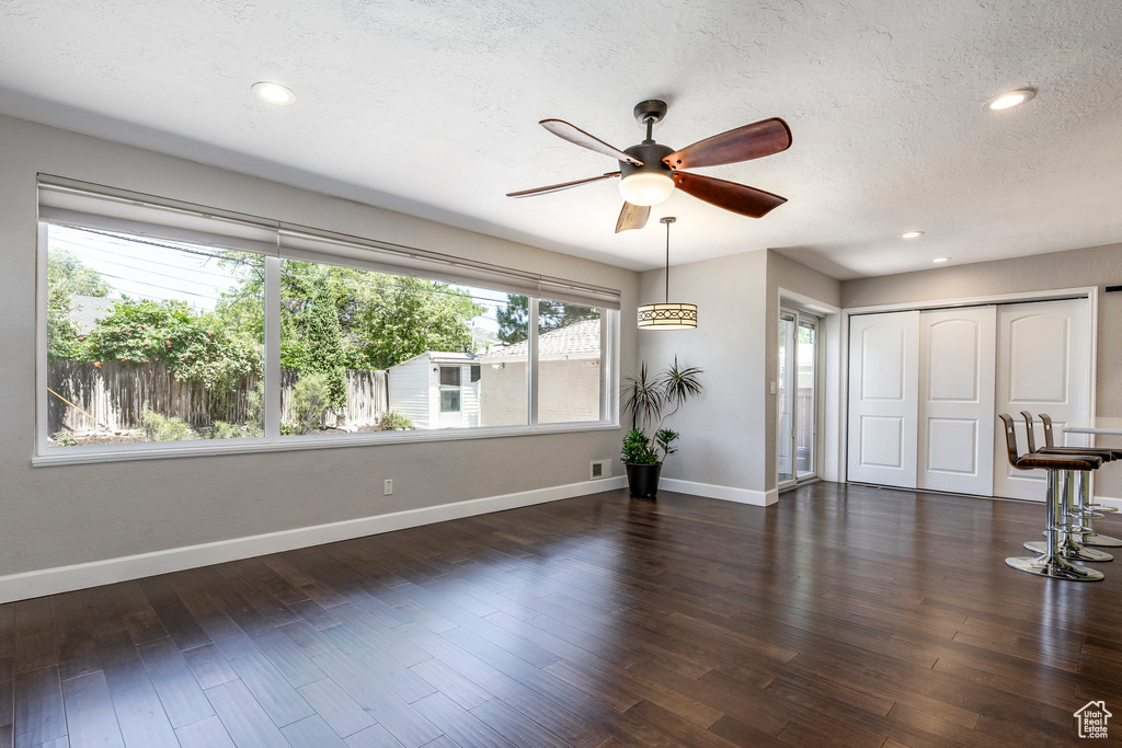 Unfurnished living room featuring a ceiling fan, a textured ceiling, dark wood-style flooring, and recessed lighting