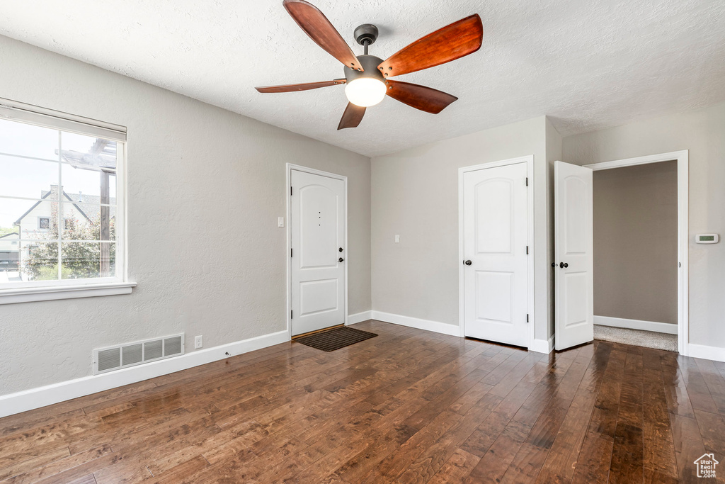 Empty room featuring hardwood / wood-style floors, a ceiling fan, and a textured ceiling
