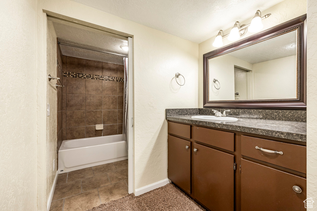 Full bathroom with vanity, shower / bath combination, a textured ceiling, and a textured wall
