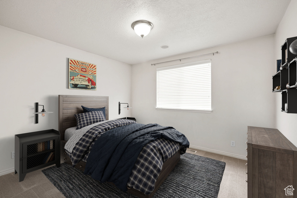 Bedroom with light carpet and a textured ceiling