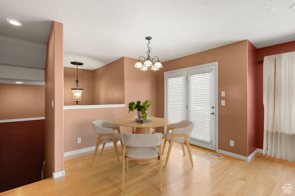 Dining space with light wood-type flooring, a textured ceiling, and a chandelier