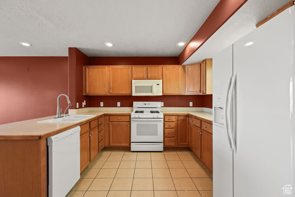 Kitchen featuring white appliances, light countertops, a peninsula, light tile patterned flooring, and recessed lighting