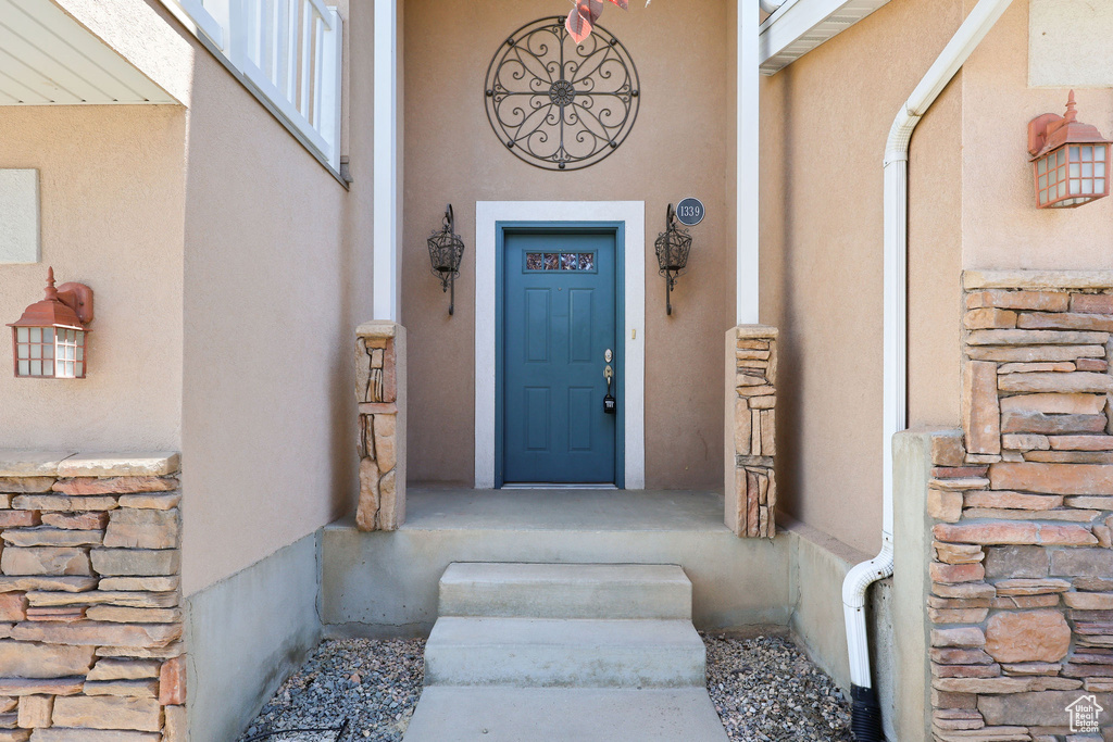 Doorway to property featuring stucco siding and stone siding