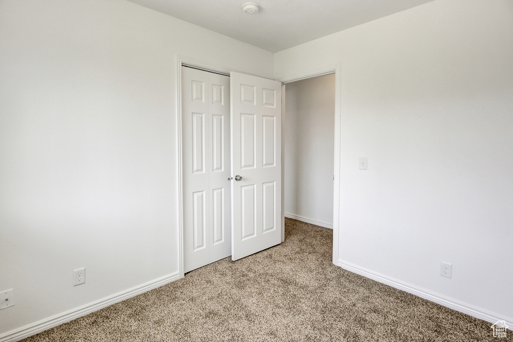 Unfurnished bedroom with light carpet and a closet