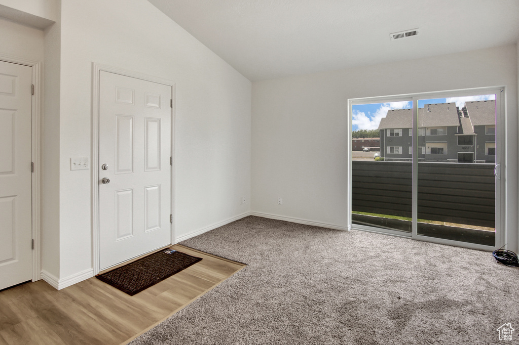 Carpeted foyer entrance with lofted ceiling and wood finished floors
