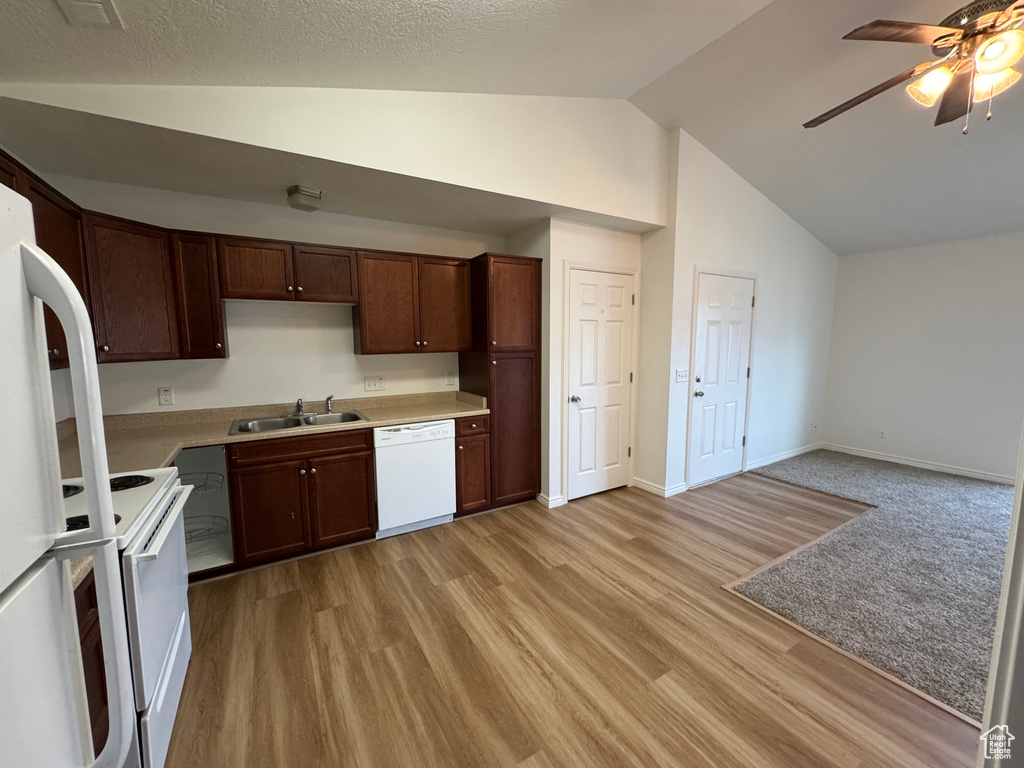 Kitchen with white appliances, ceiling fan, light countertops, light wood-style floors, and high vaulted ceiling
