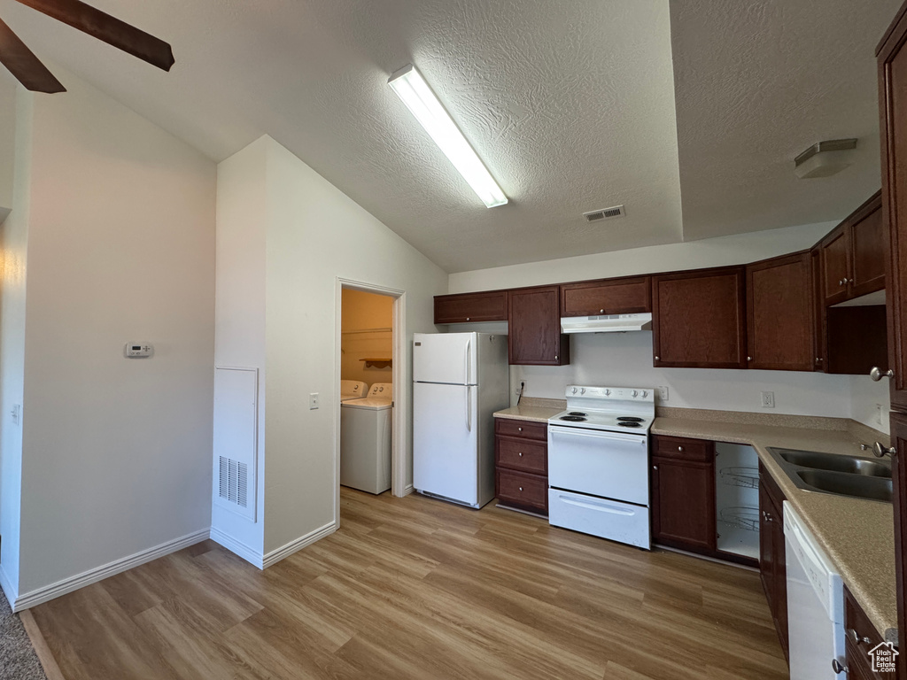 Kitchen featuring white appliances, washer and dryer, lofted ceiling, light wood finished floors, and under cabinet range hood