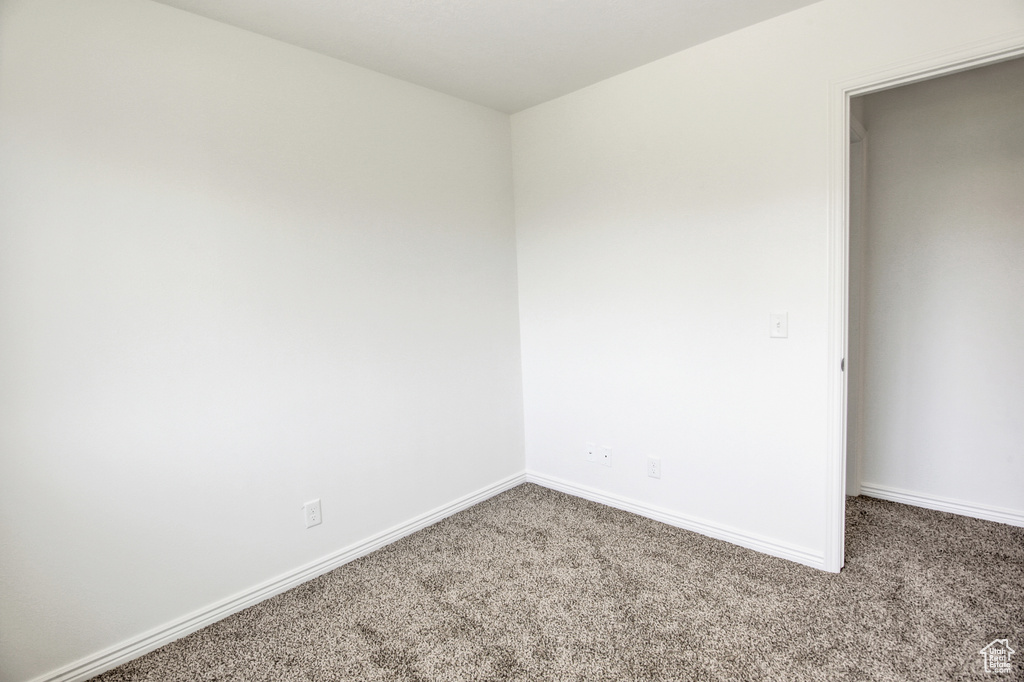 Spare room featuring carpet flooring and baseboards