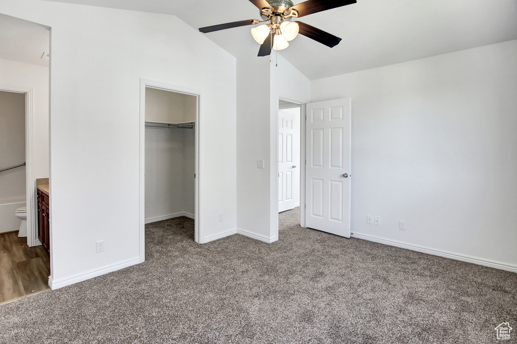 Unfurnished bedroom featuring carpet, lofted ceiling, a walk in closet, and a ceiling fan