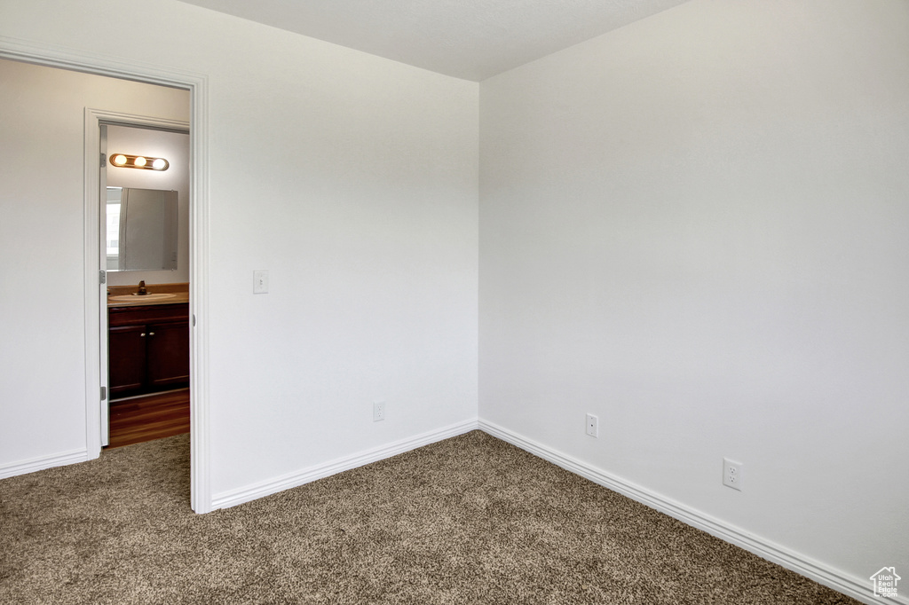 Carpeted spare room with baseboards and a sink