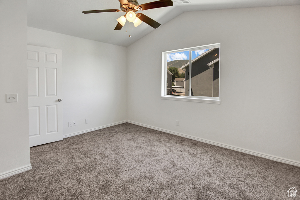 Empty room with carpet, a ceiling fan, and lofted ceiling