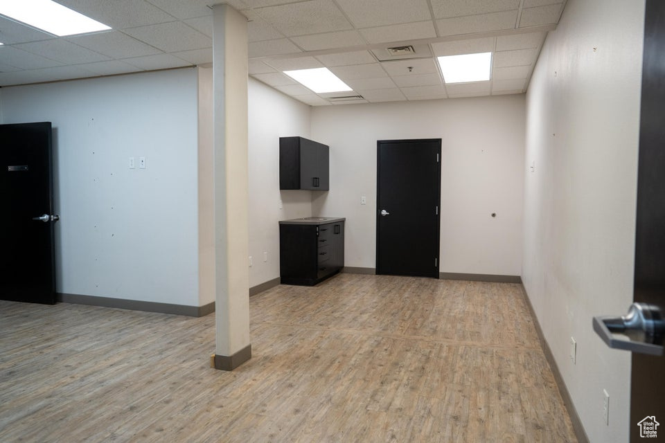 Empty room with light wood finished floors and a paneled ceiling