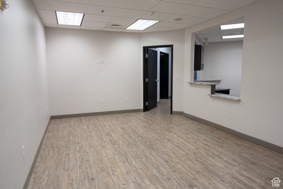 Unfurnished room featuring a paneled ceiling, wood finished floors, and fire sprinkler in ceiling