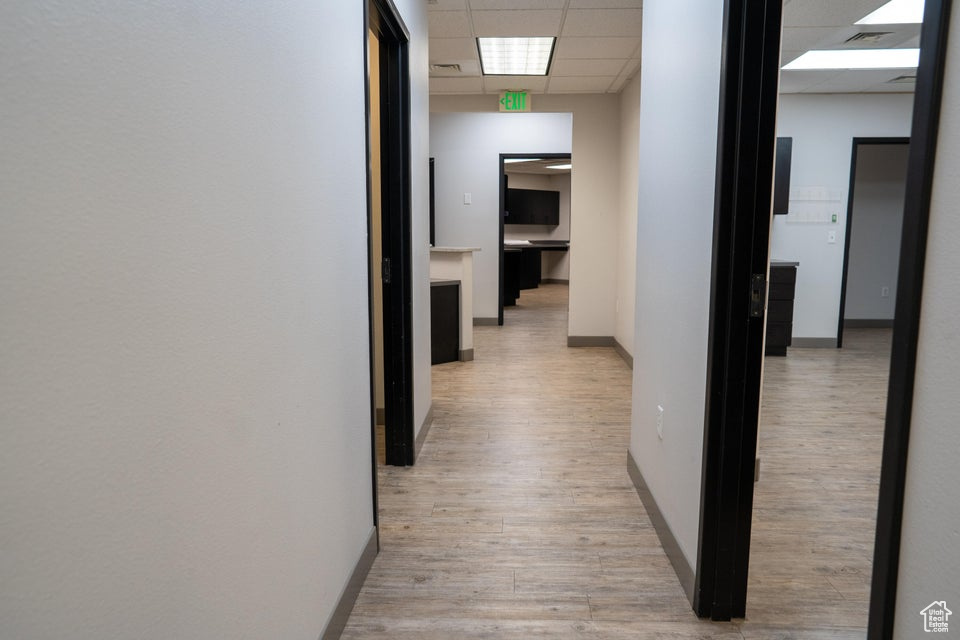 Corridor with a drop ceiling and light wood finished floors