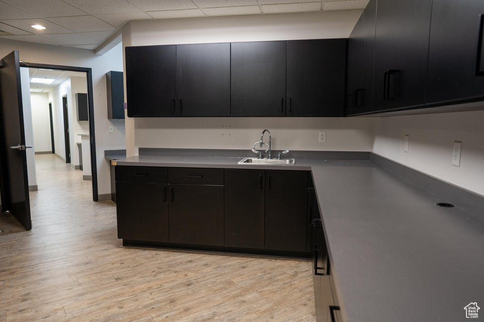 Kitchen with dark cabinets, light wood finished floors, recessed lighting, and a drop ceiling