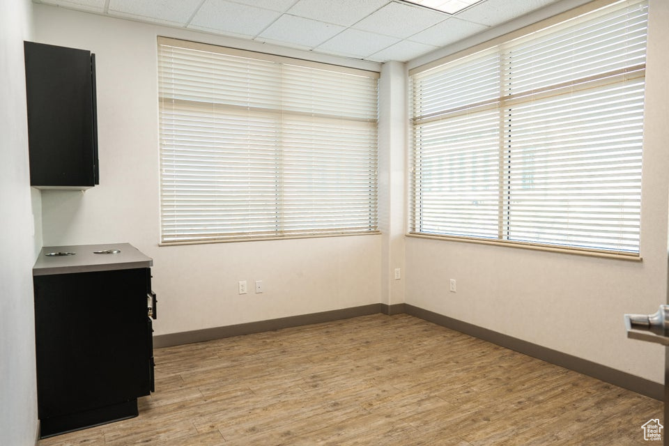Unfurnished dining area featuring a drop ceiling and light wood-style flooring