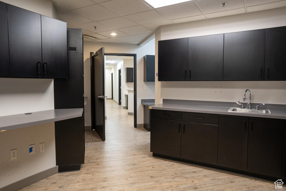 Kitchen featuring dark cabinetry, a paneled ceiling, light wood-type flooring, light countertops, and recessed lighting