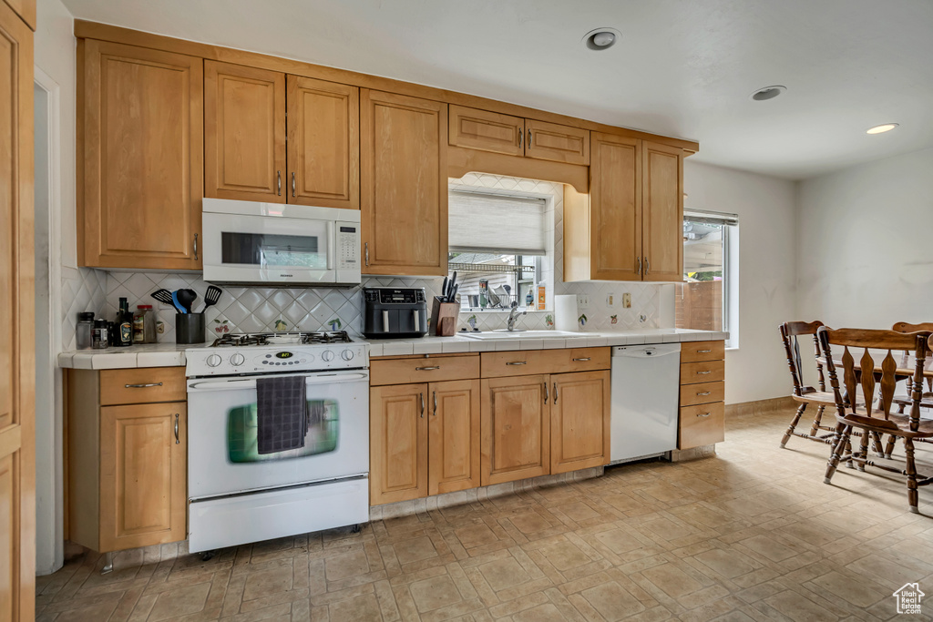 Kitchen with white appliances, tile countertops, tasteful backsplash, recessed lighting, and light flooring