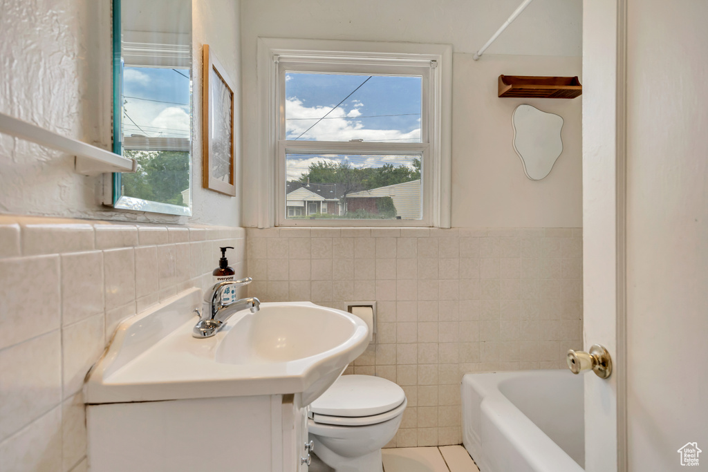 Full bath featuring tile walls, vanity, a bath, plenty of natural light, and wainscoting