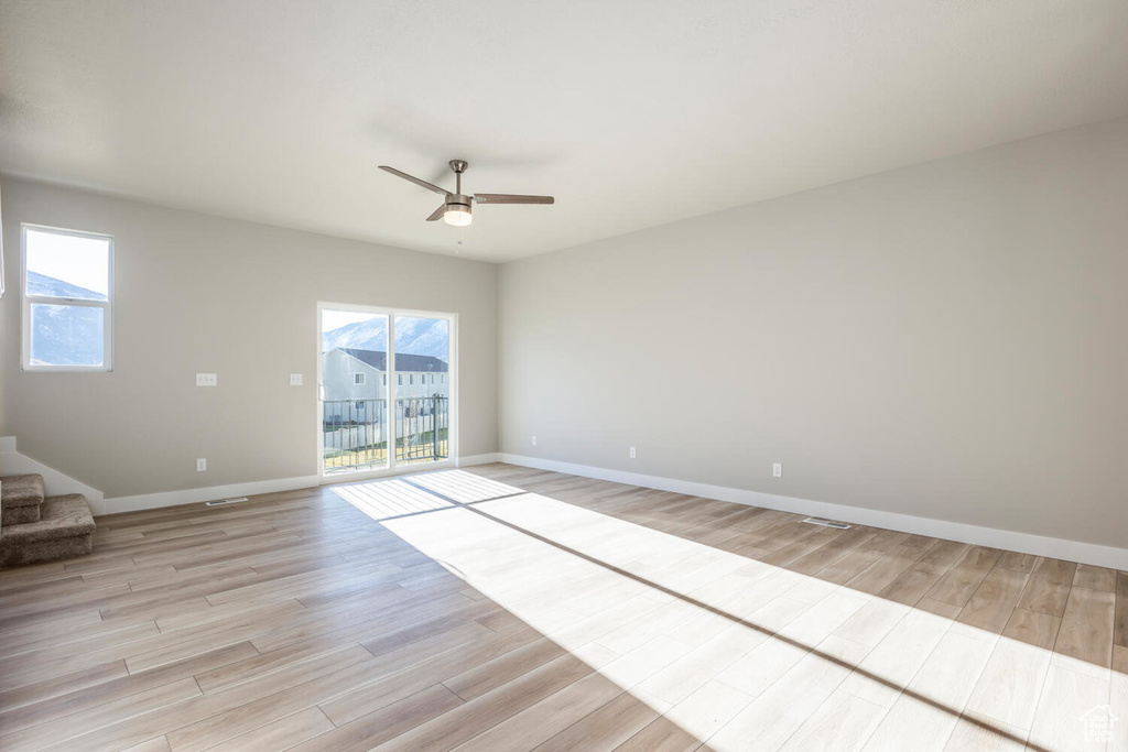 Unfurnished room featuring light wood-style flooring, healthy amount of natural light, and ceiling fan