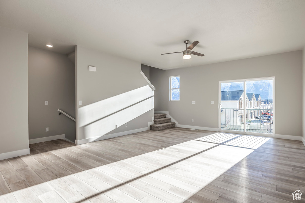 Unfurnished living room featuring a ceiling fan, wood finished floors, stairway, and recessed lighting