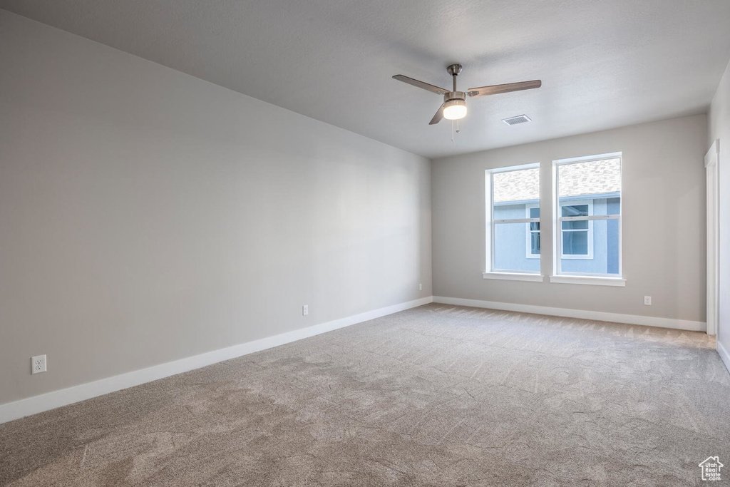Carpeted empty room featuring ceiling fan and baseboards