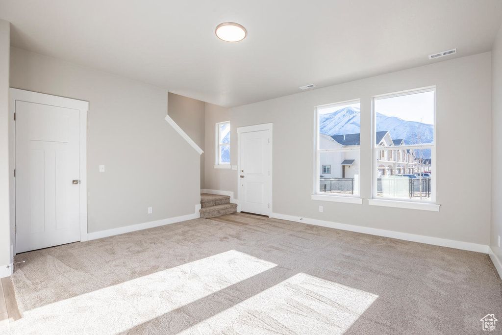 Unfurnished living room featuring stairs and carpet