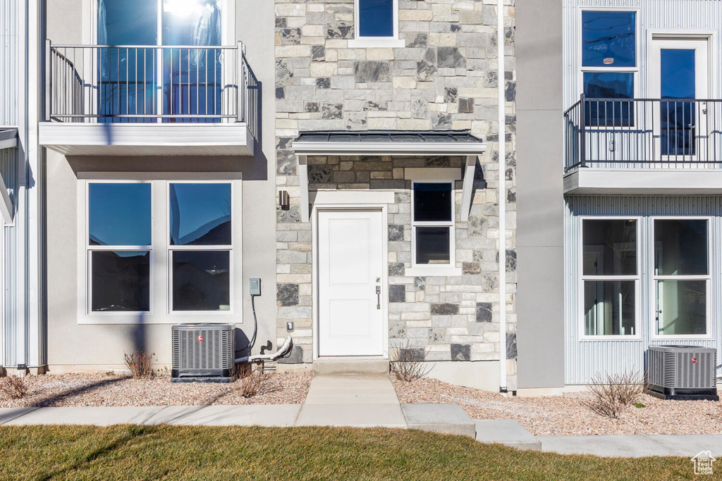 Entrance to property with stone siding and a balcony