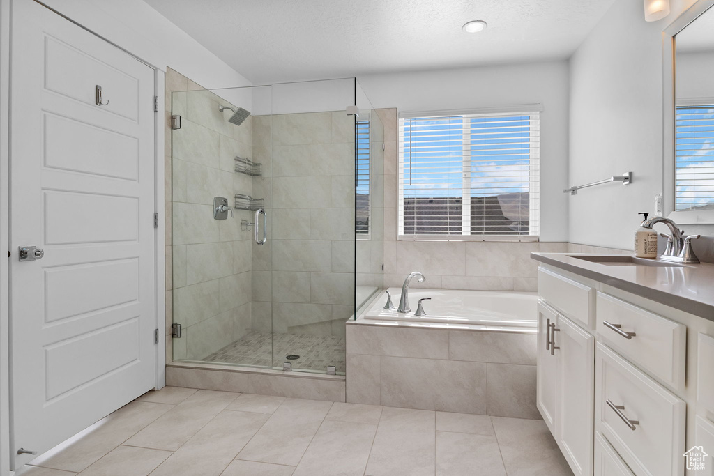 Bathroom featuring tile patterned floors, vanity, a bath, and a stall shower