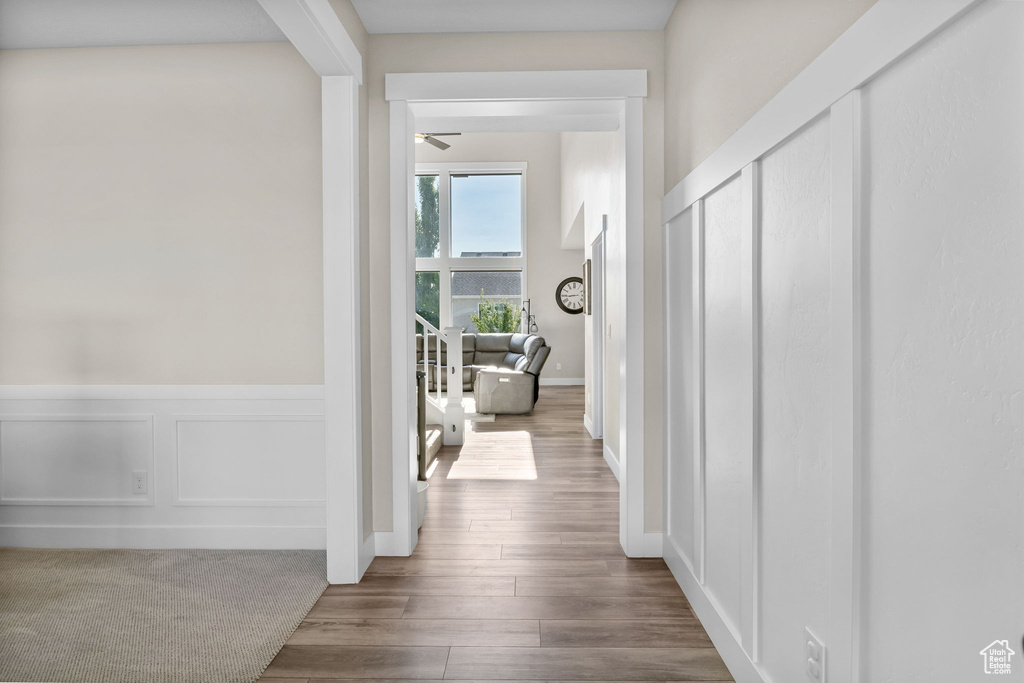 Hall featuring a wainscoted wall, wood finished floors, and a decorative wall